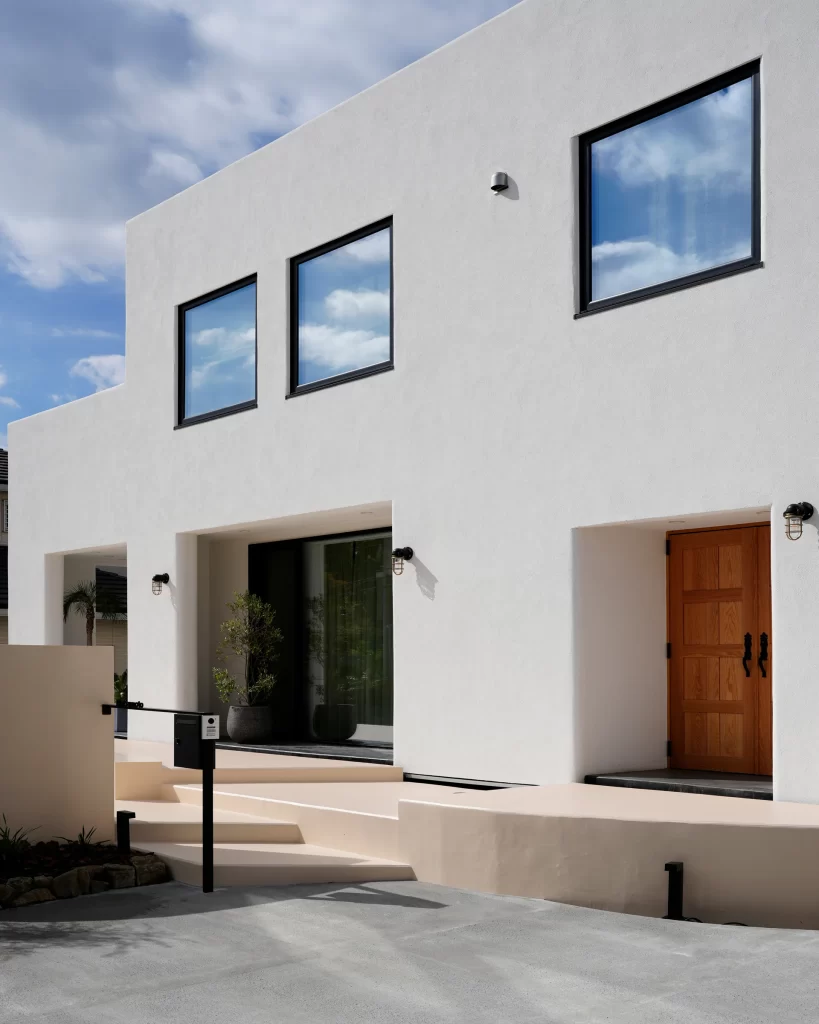 「白い漆喰外壁と木製ドアが印象的な湘南の高級注文住宅外観|自然素材を生かした上質な家づくり」