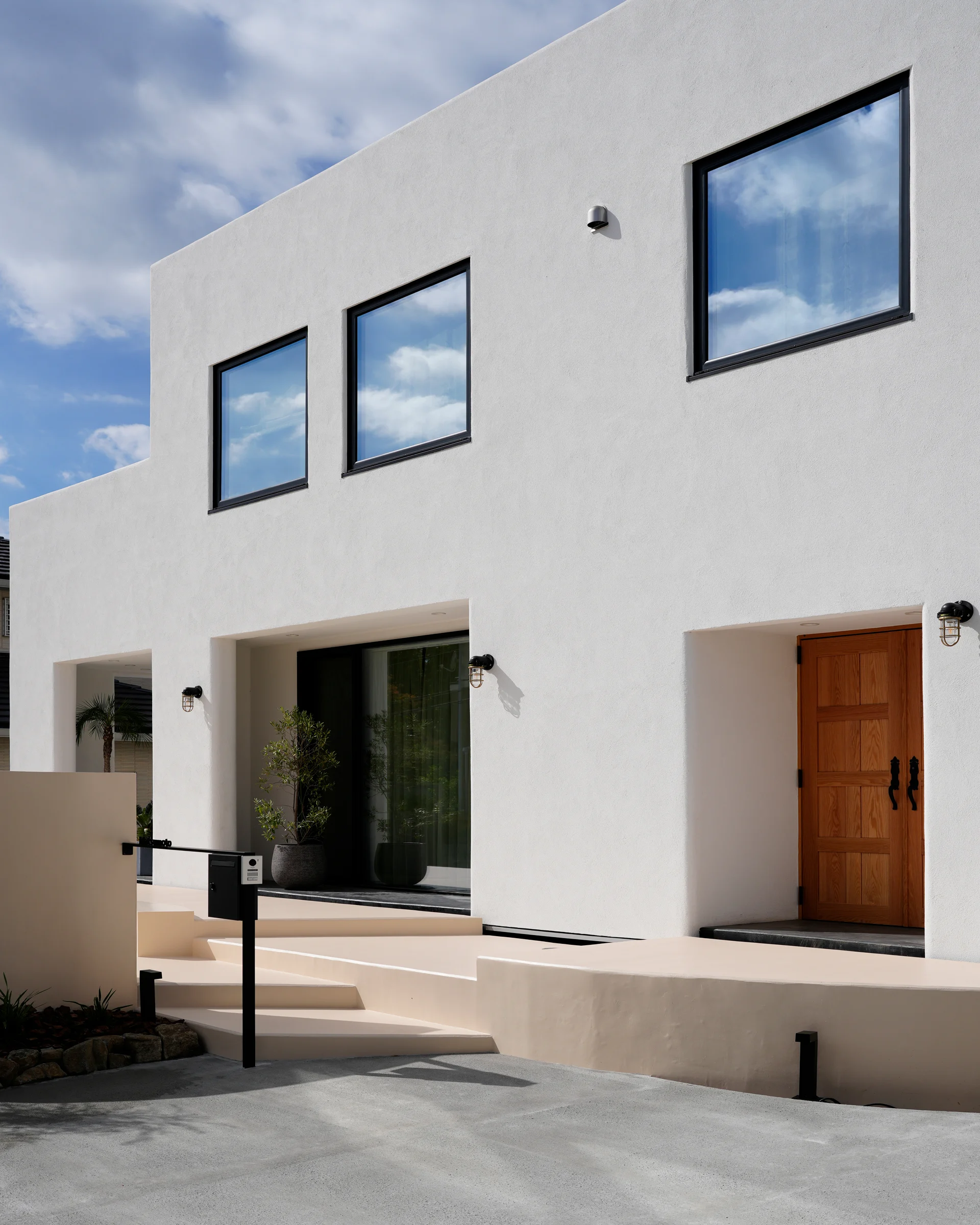 「白い漆喰外壁と木製ドアが印象的な湘南の高級注文住宅外観｜自然素材を生かした上質な家づくり」